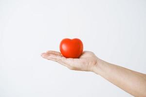 la main d'un homme tenant un coeur rouge sur fond blanc photo