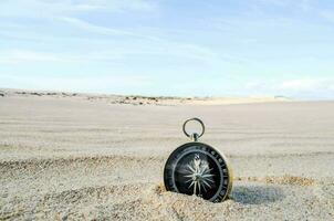 une boussole est séance dans le le sable sur une plage photo