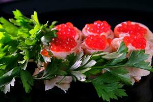 des sandwichs avec rouge caviar, décoré avec herbes sur une foncé Contexte. délicieux en bonne santé nourriture petit déjeuner le déjeuner dîner photo