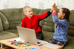 distance apprentissage en ligne éducation. école garçon et fille en train d'étudier à Accueil avec portable carnet et Faire devoirs. séance à une table photo