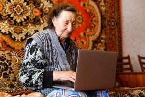 aîné femme en utilisant une portable ordinateur à Accueil photo