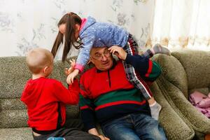 grand-père dépense temps avec petits enfants dans le vivant pièce photo