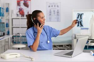 médical infirmière en portant patient radiographie dans hôpital bureau. radiologue dans médical uniforme en portant et à la recherche à radiographie, examen, os, praticien, analyser, diagnostic. photo