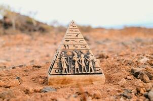 une pyramide en forme de objet avec égyptien symboles et gens sur il photo