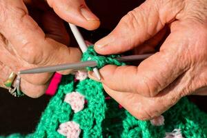 une femme mains sont en portant une vert crocheté sac photo