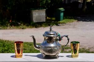 une argent thé pot et deux coloré tasses sur une table photo