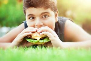 adolescent garçon en mangeant Burger photo