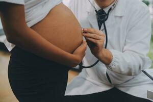 femelle médecin est vérification Enceinte femme avec stéthoscope. concept soins pour Enceinte femme photo