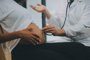 femelle médecin est vérification Enceinte femme avec stéthoscope. concept soins pour Enceinte femme photo