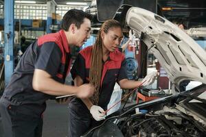 Masculin professionnel automobile superviseur conseille et inspecte noir femelle mécanicien ouvrier à propos liquide moteur pétrole à voiture garage, un service entretien, et fixation spécialiste métiers auto industrie. photo