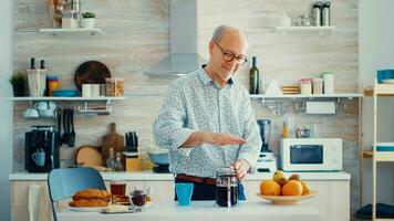 content Sénior homme pousser sur français presse tandis que en train de préparer café pour petit déjeuner. personnes âgées la personne dans le Matin profiter Frais marron café Expresso tasse caféine de ancien tasse, filtre se détendre rafraîchissement photo