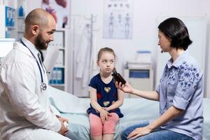 mère de malade enfant en portant pilules bouteille de médecin après médical examen. soins de santé médecin spécialiste dans médicament fournir santé se soucier prestations de service traitement examen. photo