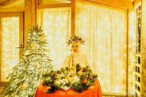 content souriant femme dans une blanc robe en portant une Champagne verre dans de face de une Noël arbre. photo