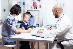 pédiatre l'écriture traitement après consultation de malade enfant dans hôpital bureau. soins de santé médecin spécialiste dans médicament fournir santé se soucier prestations de service traitement examen. photo