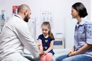 médecin donnant diagnostic à mère de malade enfant dans hôpital bureau. soins de santé médecin spécialiste dans médicament fournir santé se soucier prestations de service traitement examen. photo