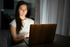 décontractée magnifique femme travail sur une portable à le nuit à maison. photo