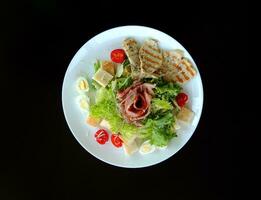 Frais Viande salade avec légumes verts sur une assiette isolé sur noir photo