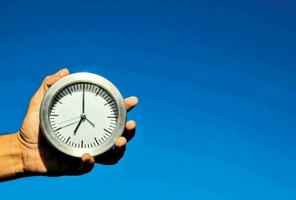 une la personne en portant une l'horloge contre une bleu ciel photo