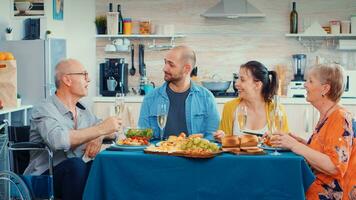 personnes âgées homme avec invalidité ayant bien nouvelles pour le sien famille. plus âgée Sénior dans fauteuil roulant souriant, en buvant du vin et en mangeant pendant une gourmet repas, profiter relaxant temps. photo