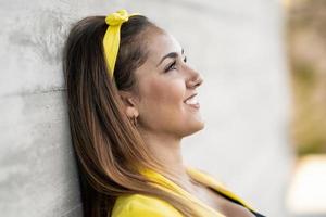 jeune femme portant une veste jaune et un bandeau souriant. photo