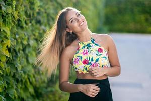 Jeune fille déplaçant ses cheveux près d'un fond de feuilles à l'extérieur photo