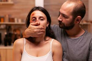 visage de effrayé femme victime tandis que homme couvertures sa bouche. violent agressif mari abuser blesser terrifié sans espoir, vulnérable, effrayé, battu et paniqué épouse. photo