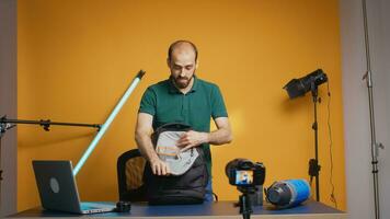 professionnel photographe en présentant sac à dos pour lentilles et caméra. montrant espace de rangement compartiments. professionnel studio vidéo et photo équipement La technologie pour travail, photo studio social médias étoile et influenceur