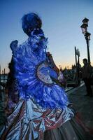 une femme habillé dans une bleu et violet costume est permanent sur le rue photo