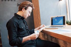 homme d'affaires utilisant un ordinateur portable avec une tablette et un stylo sur une table en bois dans un café avec une tasse de café. un entrepreneur qui gère son entreprise à distance en tant qu'indépendant. photo
