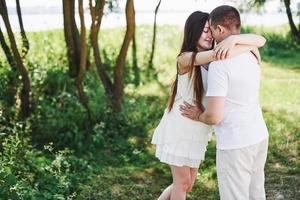 heureux et jeune couple enceinte s'embrassant dans la nature photo