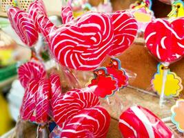 fermer et cultures coloré sucré sucettes avec Étiquettes pour vente sur en bois étagère Contexte. photo