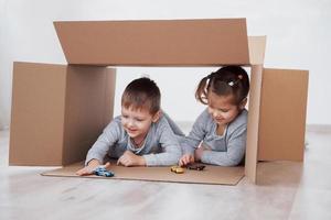 petit frère et petite soeur jouant dans des boîtes en carton en pépinière photo