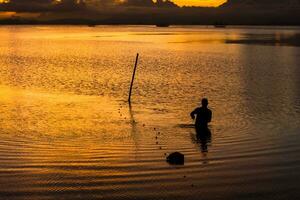 silhouette de les pêcheurs dans le Lac après le coucher du soleil. photo