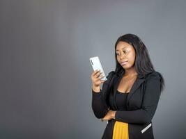africain fille en portant à la recherche à mobile téléphone envoyer des SMS bavarder sur téléphone portable photo