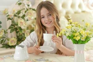 souriant peu fille en portant gros tasse de thé photo