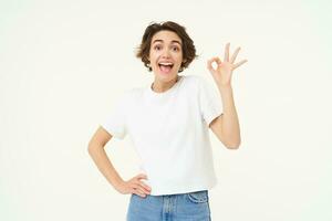 non problème. portrait de Jeune femme permanent dans sur de soi pose, spectacles d'accord, d'accord, zéro geste, des stands plus de blanc studio Contexte photo