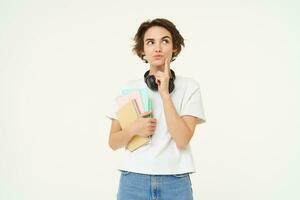 portrait de brunette femme pensée, étudiant avec des cahiers, à la recherche réfléchi, fabrication décision, permanent plus de blanc studio Contexte photo