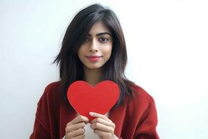 ai généré une jeune, attrayant femme avec foncé cheveux en portant une rouge en forme de coeur signe. elle apparaît à être posant pour le photo, peut-être convoyer une message ou émotion connecté à le cœur symbole. photo