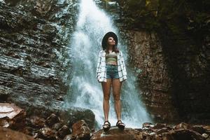 femme au chapeau brun, profitant de la vue sur la cascade photo