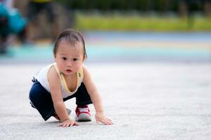 asiatique peu enfant garçon entraine toi à en marchant à parc. bambin chute et séance à le sol. fils a essayé à supporter en haut encore. enfant exercice pour santé. développement de bébé vieilli de 1 année vieux. photo