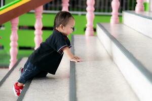 le un ans adorable enfant garçon grimpe en haut le escaliers. développement bambin bébé fils mouvement équilibre et coordination. le concept de content enfance. photo