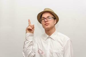 le Jeune gars dans des lunettes et une chapeau points une doigt à le Haut. photo