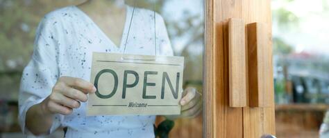 affaires femme propriétaire ouvert sur le premier journée de entreprise. garanties sécurité, propreté, ouvert le café magasin. ouvert pour Nouveau normal. petit entreprise, accueillir, restaurant, Accueil fabriqué photo