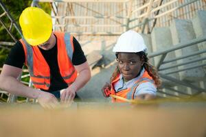 Masculin et femelle ingénieurs travail sur construction placer, elles ou ils sont inspecter le ciment plâtre travail sur le des murs et balcons de le bâtiment. photo