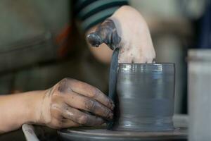 mains de une potier, création un en terre pot sur le poterie roue photo