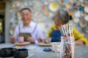 dans le poterie atelier, un asiatique retraité couple est engagé dans poterie fabrication et argile La peinture activités. photo