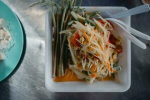 épicé Papaye salade délicieux ou somtum est une thaïlandais nourriture servir sur mousse plateau photo