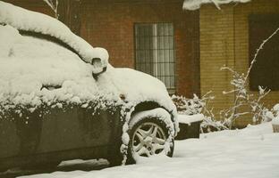 fragment de la voiture sous une couche de neige après une forte chute de neige. le corps de la voiture est recouvert de neige blanche photo