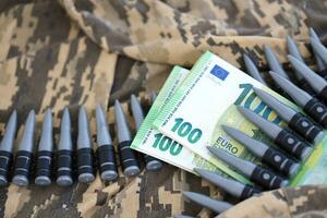 liasses de euro factures et une machine pistolet ceinture sur le camouflage uniforme de une ukrainien soldat. concept de guerre financement, pot-de-vin ou don photo