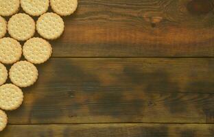 un biscuit sandwich rond fourré à la noix de coco se trouve en grande quantité sur une surface en bois marron. photo de friandises comestibles sur un fond en bois avec espace de copie